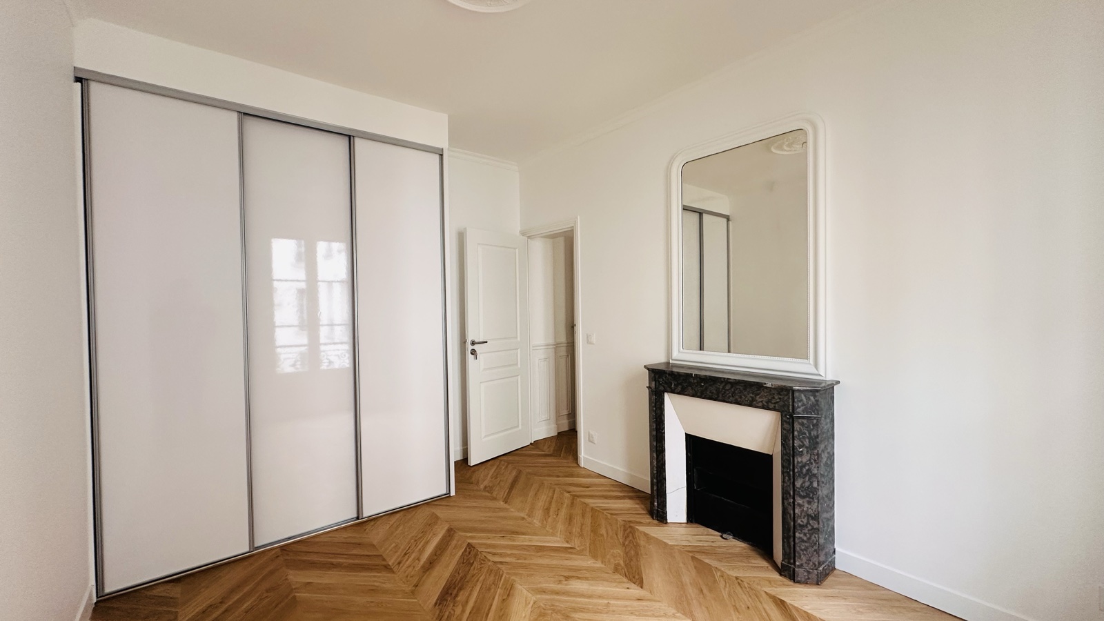 La chambre : placard toute hauteur à façades lisses, cheminée de marbre noir et trumeau d'origine.
