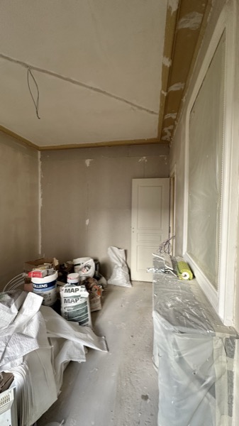 La même pièce pendant le chantier : murs mis à nu, sols protégés, matériaux en attente.