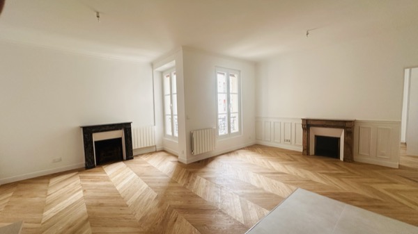 Séjour rénové d'un appartement parisien, parquet Point de Hongrie et moulures d'origine restaurées.